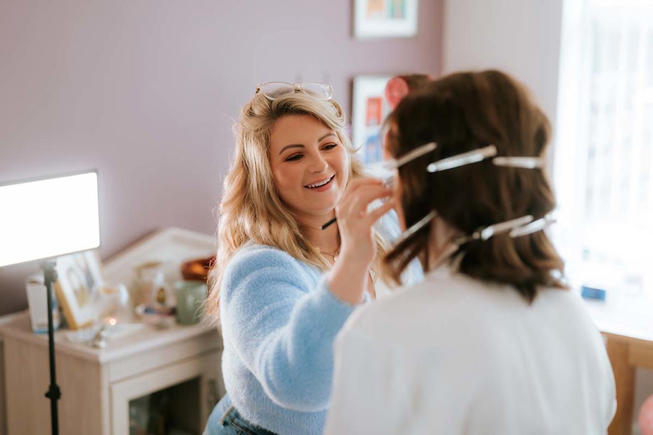 makeup artist doing makeup with bride facing towards her